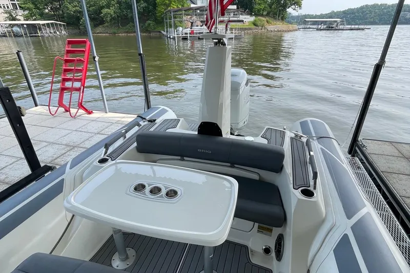 Slide: The Image of 2022 Brig Eagle 8 boat docked by a serene lake with seating and table. - 15