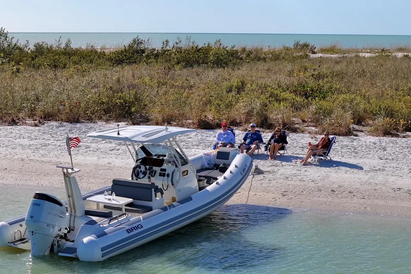 Slide: The Image of 2022 Brig Eagle 8 boat docked on a sandy beach with people relaxing nearby. - 4