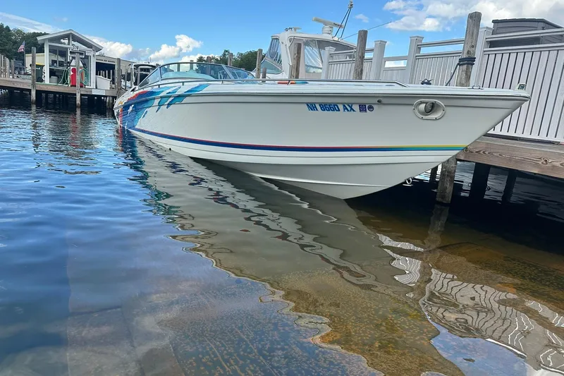 Slide: The Image of 1998 Formula 353 FASTech boat docked on clear water under a blue sky. - 2