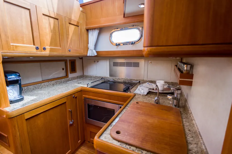 Slide: The Image of Luxurious 2012 Grand Banks 46 Eastbay SX yacht kitchen with wooden cabinetry and granite countertops. - 13