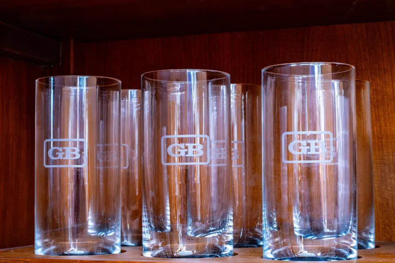 Slide: The Image of Clear glassware with "GB" logo on wooden shelf, Grand Banks 46 Eastbay SX, 2012. - 14