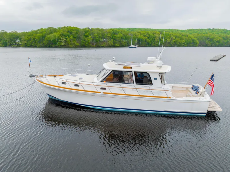 Slide: The Image of 2012 Grand Banks 46 Eastbay SX yacht on calm water, surrounded by lush greenery. - 2