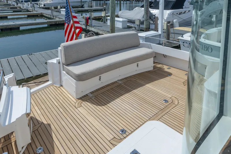 Slide: The Image of Teak deck of 2012 Grand Banks 46 Eastbay SX with cushioned seating and American flag. - 4