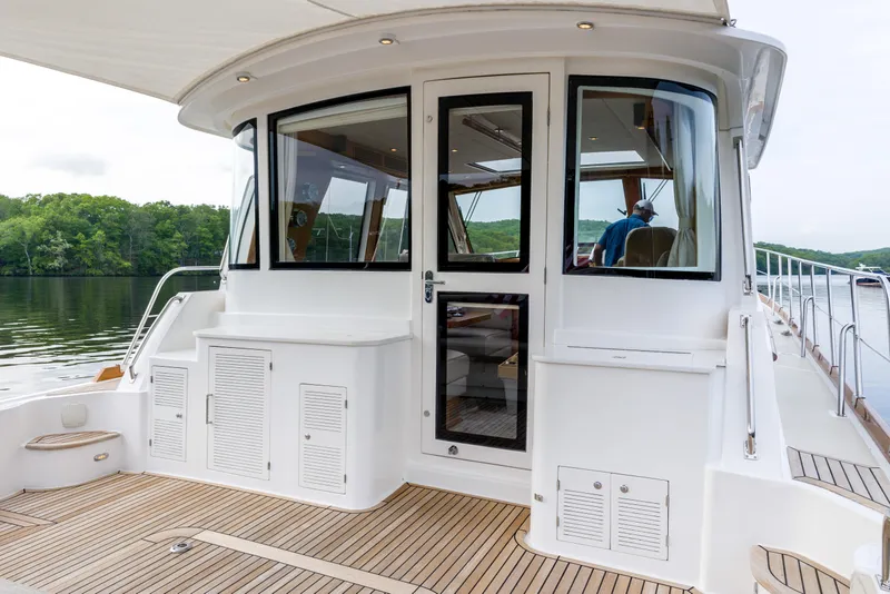 Slide: The Image of Grand Banks 46 Eastbay SX 2012 yacht with teak deck and glass doors on a serene waterway. - 42