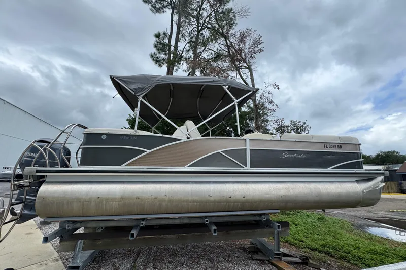 The Image of 2017 Sweetwater Premium Edition 255 SL pontoon boat on a trailer, under cloudy skies. - 1