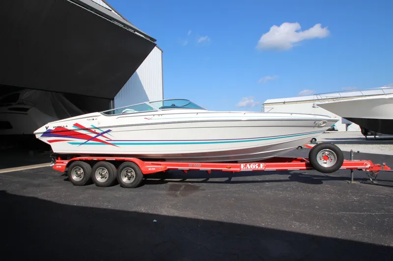 Slide: The Image of 1995 Formula SR1 303 boat on red trailer, parked outdoors under blue sky. - 8