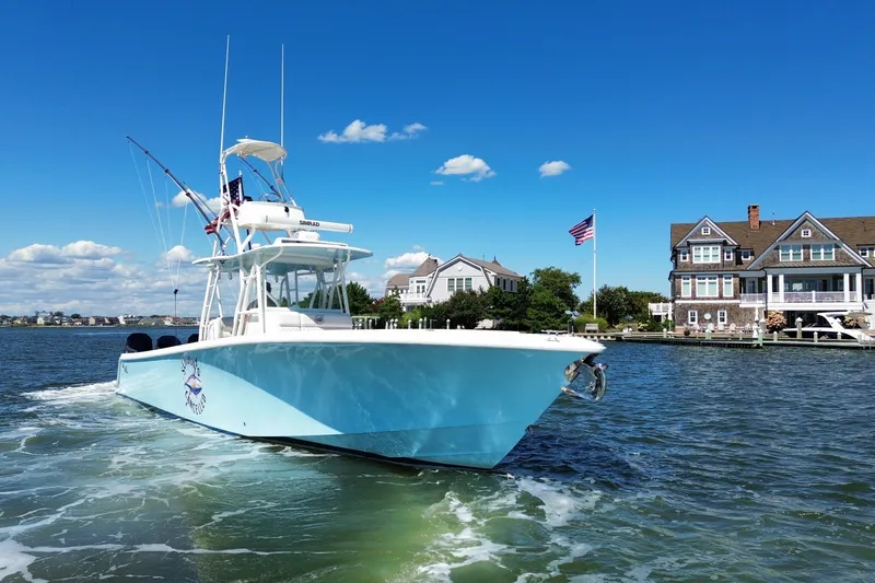 Slide: The Image of 2018 SeaVee 390Z boat cruising near waterfront homes under a clear blue sky. - 10