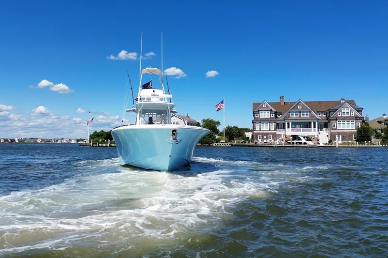Slide: The Image of 2018 SeaVee 390Z boat cruising near waterfront homes under a clear blue sky. - 13