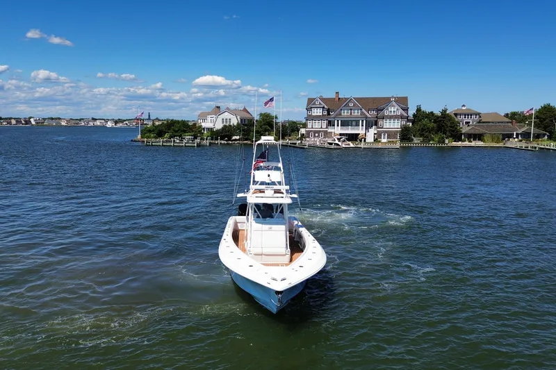 Slide: The Image of 2018 SeaVee 390Z boat cruising near waterfront homes under a clear blue sky. - 16
