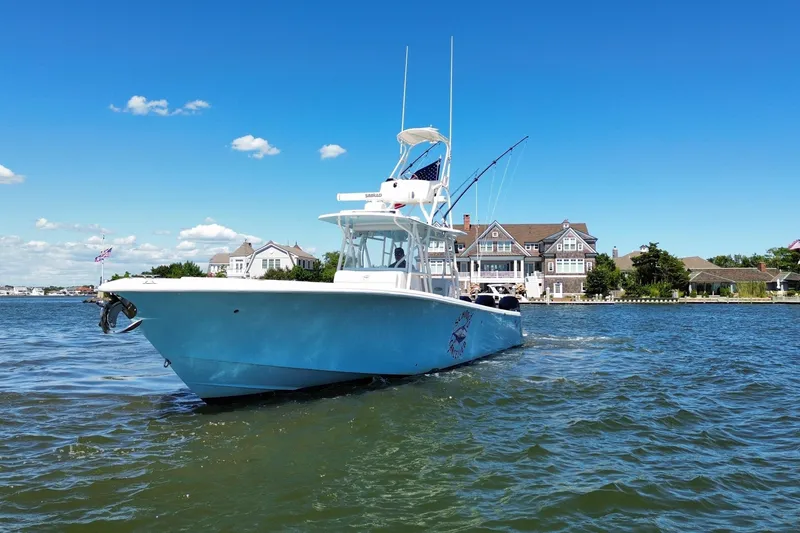 Slide: The Image of 2018 SeaVee 390Z boat on water, with coastal houses in the background under a clear blue sky. - 17