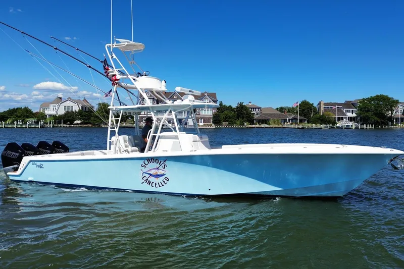 Slide: The Image of 2018 SeaVee 390Z boat on water, blue hull, fishing rods, coastal homes in background. - 8