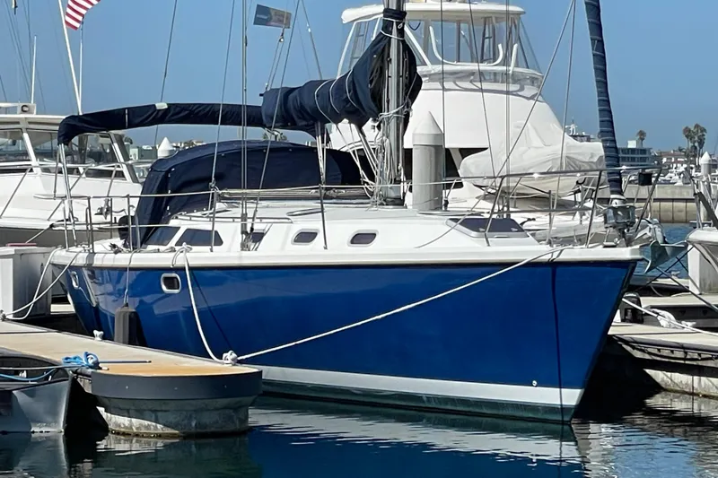 The Image of Blue 2001 Catalina 42 sailboat docked at marina with American flag in background. - 0