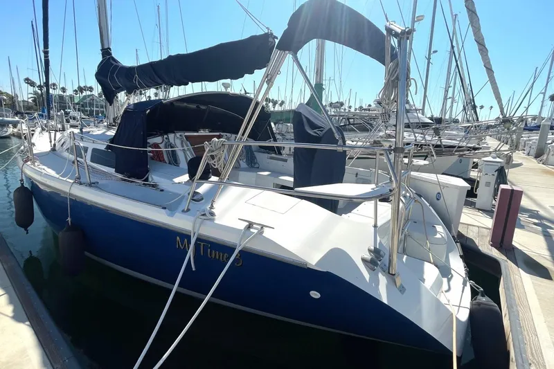 Slide: The Image of 2001 Catalina 42 sailboat docked in marina, featuring blue hull and covered cockpit. - 2
