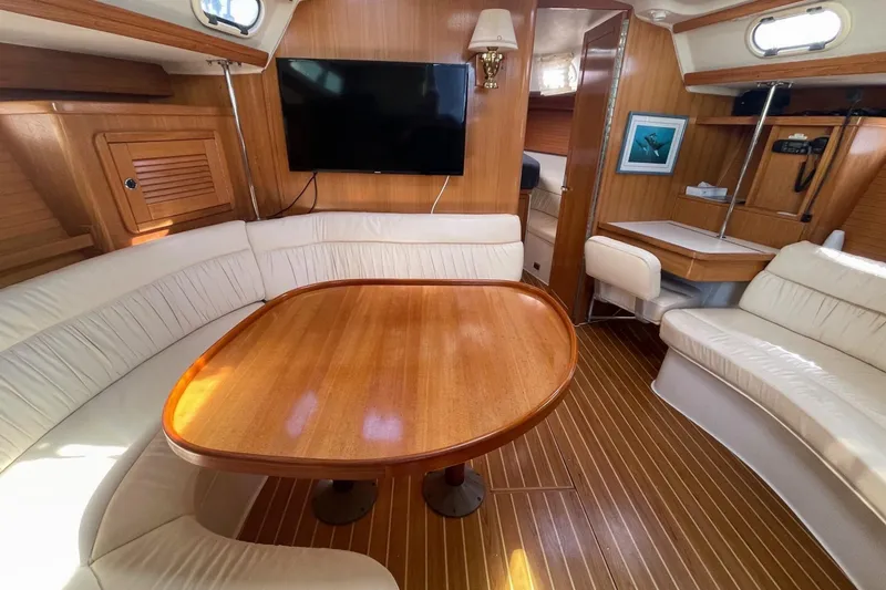 Slide: The Image of Interior of 2001 Catalina 42 sailboat with wood table, white seating, and mounted TV. - 8