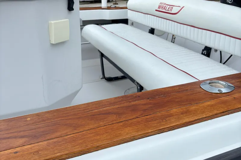 Slide: The Image of 1996 Boston Whaler 21 Outrage boat interior with white seating and wooden trim. - 11