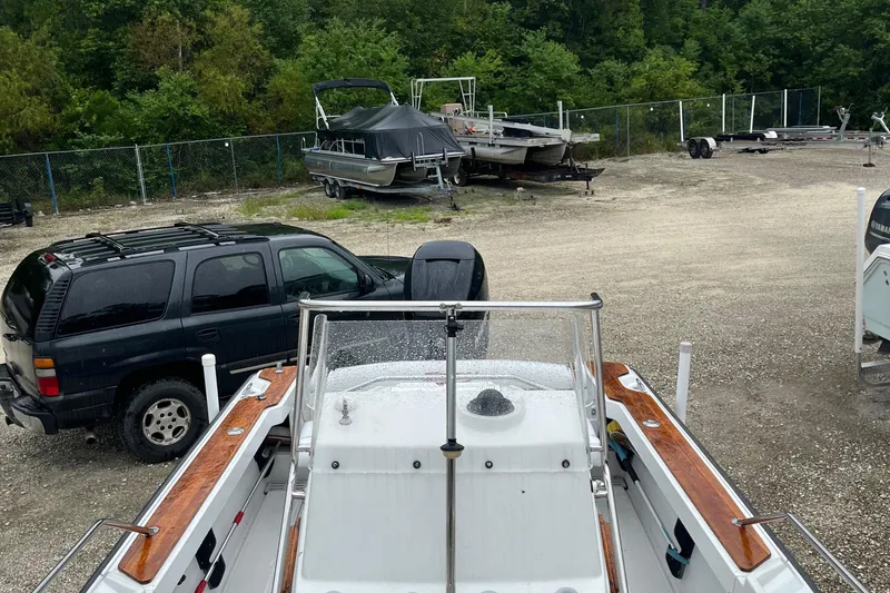 Slide: The Image of 1996 Boston Whaler 21 Outrage boat in storage yard with vehicles and trailers. - 6