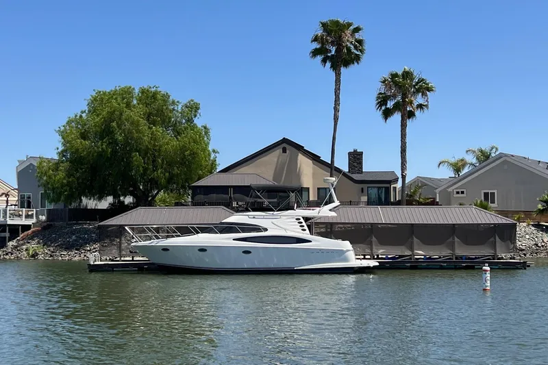 Slide: The Image of 2002 Regal Commodore 3880 yacht docked by waterfront homes, surrounded by palm trees. - 1