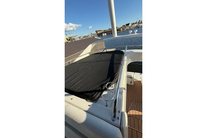 Slide: The Image of 2002 Regal Commodore 3880 yacht deck with black cover, docked by waterfront. - 19