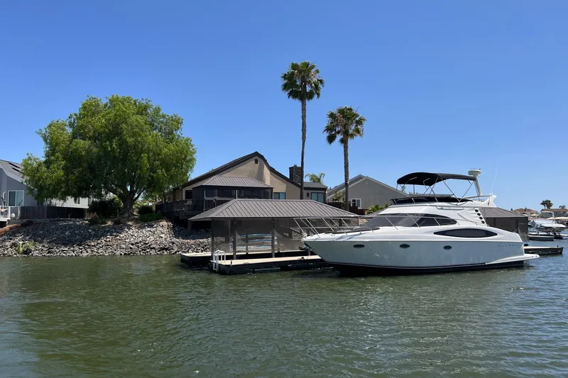 Slide: The Image of 2002 Regal Commodore 3880 yacht docked by waterfront homes with palm trees. - 2