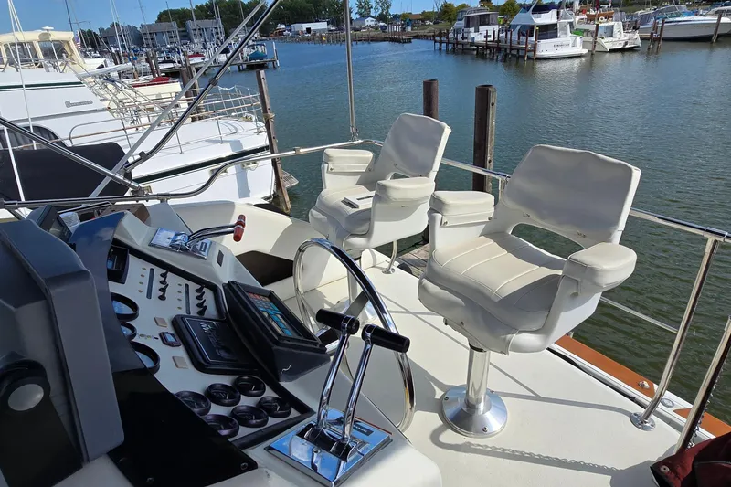 Slide: The Image of 1987 Trojan 10.8 Meter Sedan boat cockpit with dual captain chairs and control panel, docked at marina. - 22