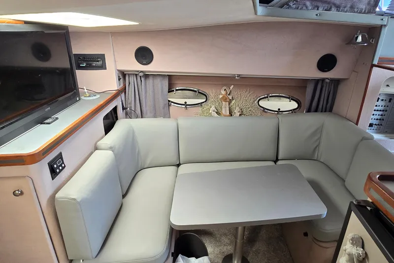 Slide: The Image of 1987 Trojan 10.8 Meter Sedan interior with gray seating, table, and TV. - 29