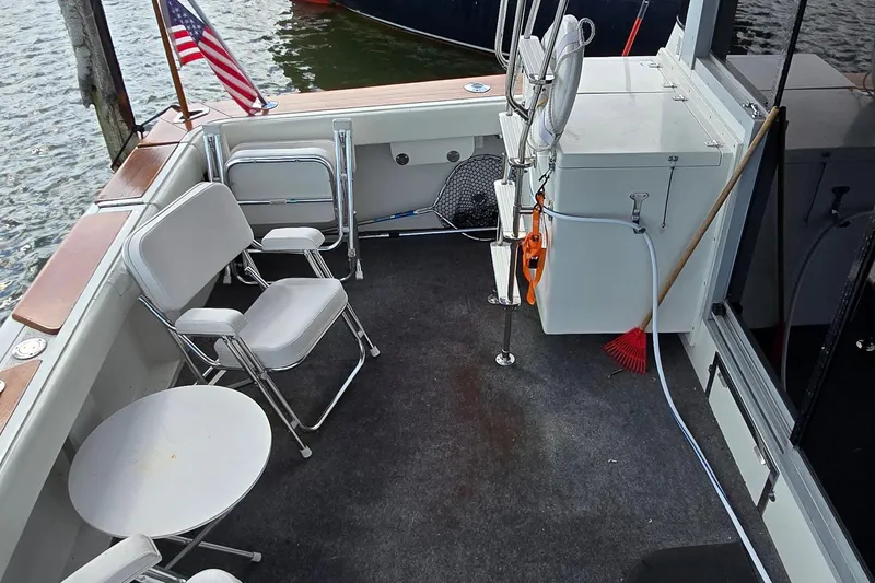 Slide: The Image of 1987 Trojan 10.8 Meter Sedan boat deck with chairs, American flag, and cleaning tools. - 18