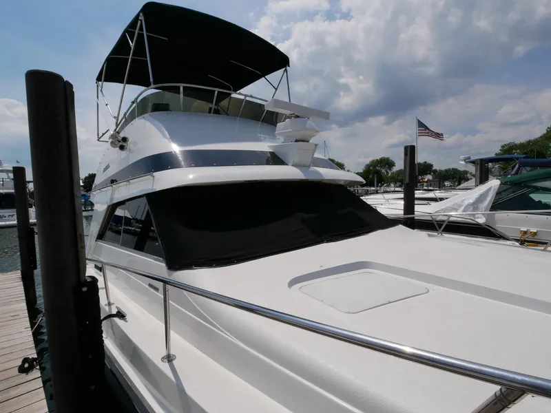 Slide: The Image of 1987 Trojan 10.8 Meter Sedan yacht docked at a marina under a partly cloudy sky. - 5