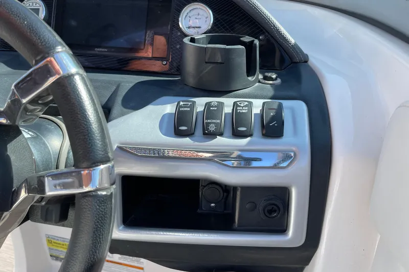 Slide: The Image of Dashboard controls of a 2016 Regal 23 OBX boat, featuring steering wheel and switches. - 22