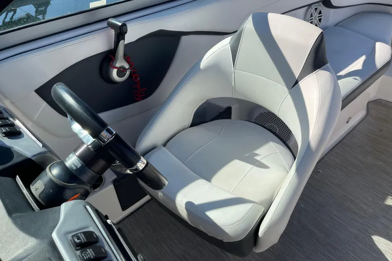Slide: The Image of 2016 Regal 23 OBX boat interior with steering wheel and cushioned seat. - 23
