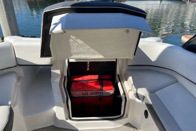 Slide: The Image of 2016 Regal 23 OBX boat storage compartment with life jackets, docked by the water. - 29