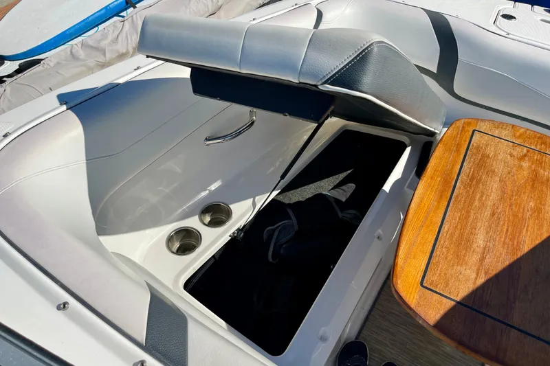 Slide: The Image of 2016 Regal 23 OBX boat interior with open storage compartment and wooden table. - 46