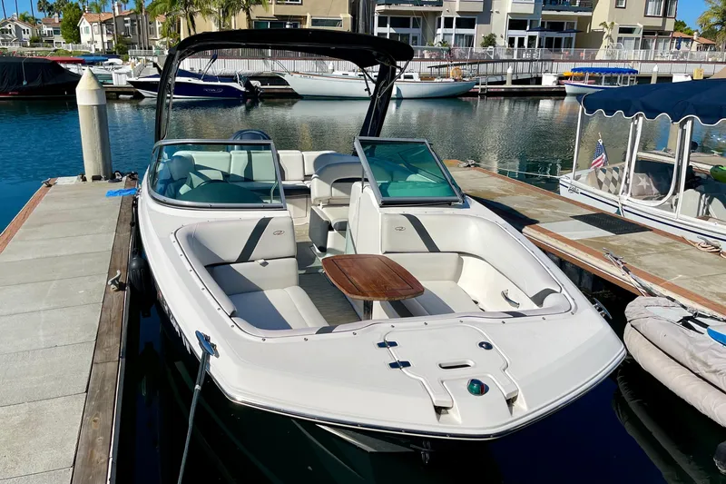 Slide: The Image of 2016 Regal 23 OBX boat docked in a marina, featuring spacious seating and a wooden table. - 6
