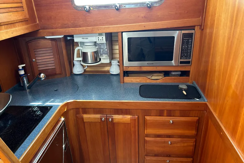 Slide: The Image of Wooden yacht galley with microwave, coffee maker, and storage; Sabre 38, 2005 model. - 12