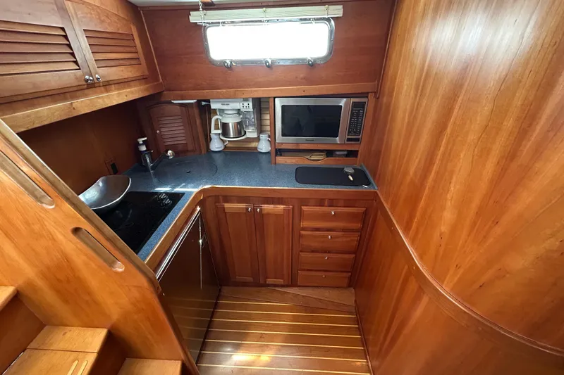 Slide: The Image of 2005 Sabre 38 yacht kitchen with wood cabinetry, sink, microwave, and coffee maker. - 13