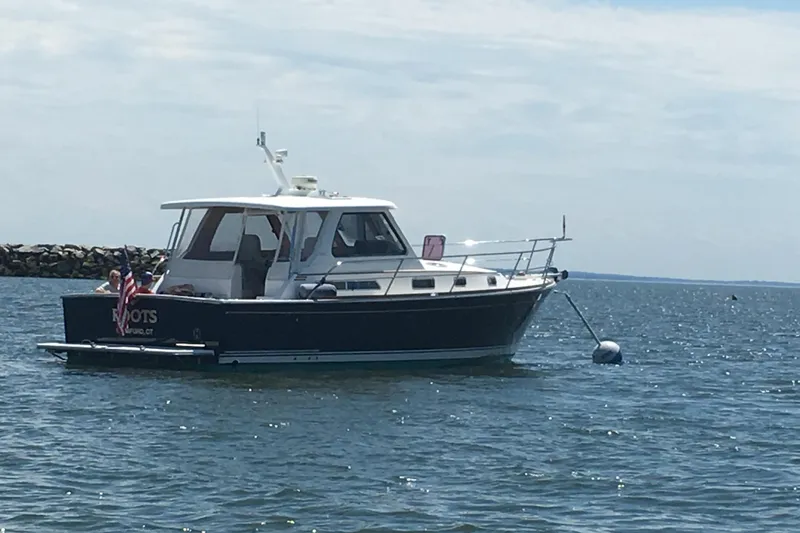Slide: The Image of 2005 Sabre 38 boat anchored on calm water with clear sky background. - 2