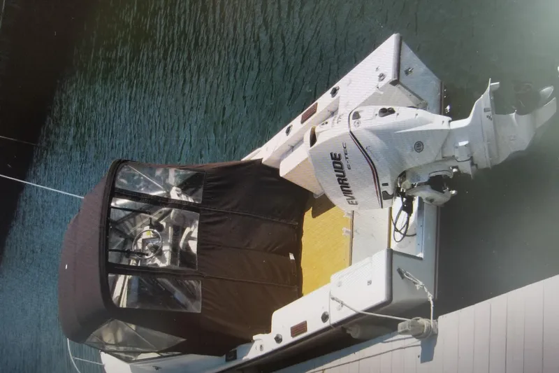 Slide: The Image of 1982 Mako 228 boat with Evinrude outboard motor, docked on calm water. - 2