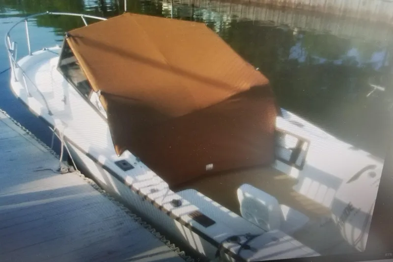Slide: The Image of 1982 Mako 228 boat with brown canopy docked on calm water. - 3