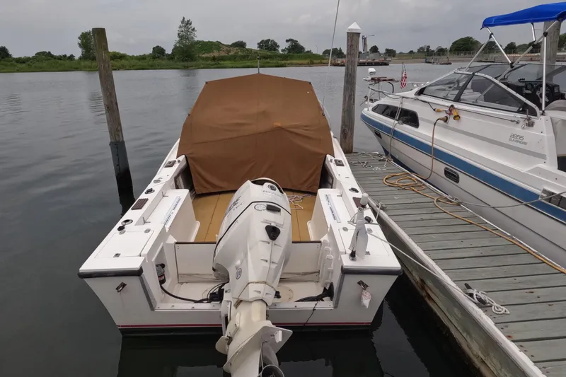 Slide: The Image of 1982 Mako 228 boat docked with cover, outboard motor visible. - 4