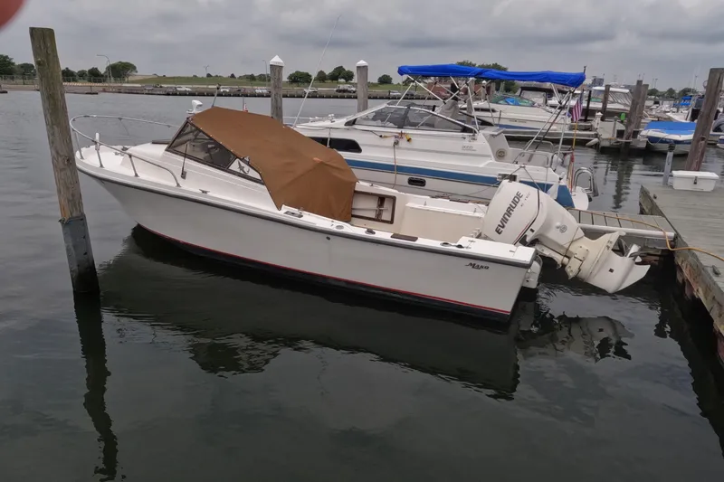 Slide: The Image of 1982 Mako 228 boat docked in marina, featuring Evinrude outboard motor. - 5