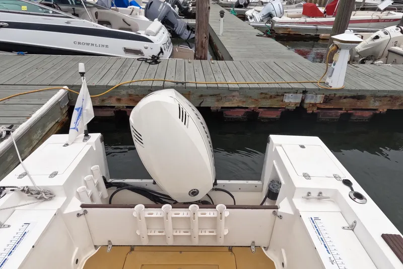 Slide: The Image of 1982 Mako 228 boat docked, featuring outboard motor and fishing rod holders. - 6