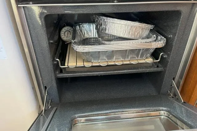 Slide: The Image of Open oven with stacked aluminum trays and a thermometer inside. - 12