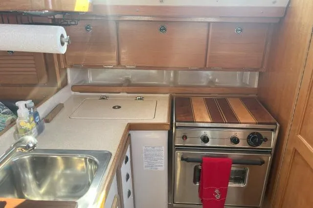 Slide: The Image of 2000 Catalina 34 Mk II yacht kitchen with sink, stove, and wooden cabinets. - 6
