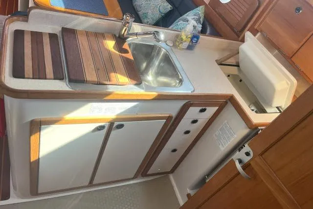 Slide: The Image of Compact kitchen area in a 2000 Catalina 34 Mk II sailboat with sink and wooden accents. - 8