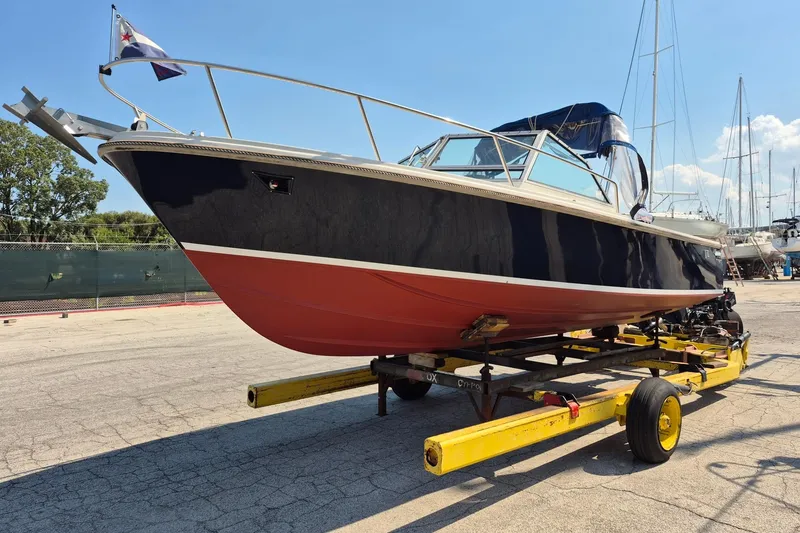 The Image of 1989 Limestone 24 boat on trailer, navy and red hull, docked outdoors. - 0