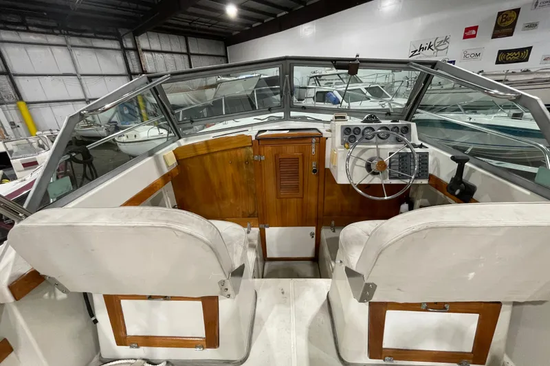 Slide: The Image of 1989 Limestone 24 boat interior with wooden dashboard and steering wheel in a storage facility. - 13