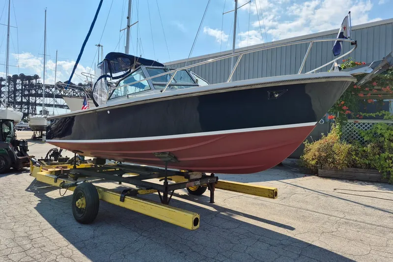 Slide: The Image of 1989 Limestone 24 boat on trailer, dockside with clear sky background. - 5