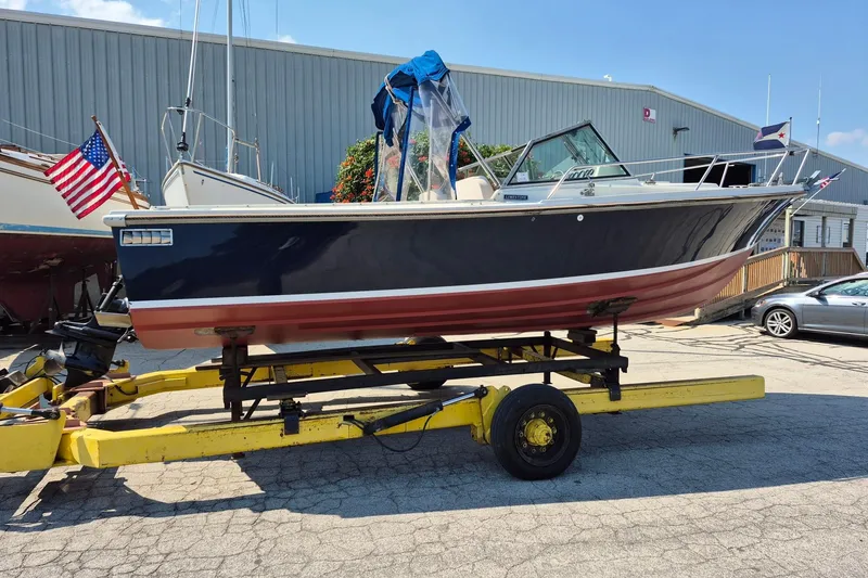 Slide: The Image of 1989 Limestone 24 boat on trailer, displayed outdoors near a warehouse. - 6
