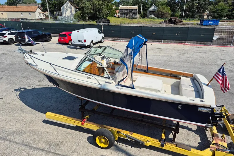 Slide: The Image of 1989 Limestone 24 boat on trailer, American flag, parked in lot. - 8