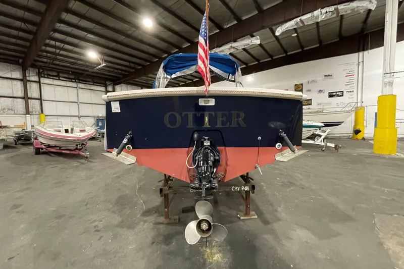 Slide: The Image of 1989 Limestone 24 boat named "Otter" in a warehouse, rear view with American flag. - 9