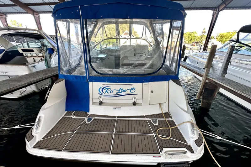 Slide: The Image of 2012 Sea Ray 330 Sundancer docked, featuring blue canopy and spacious deck area. - 1